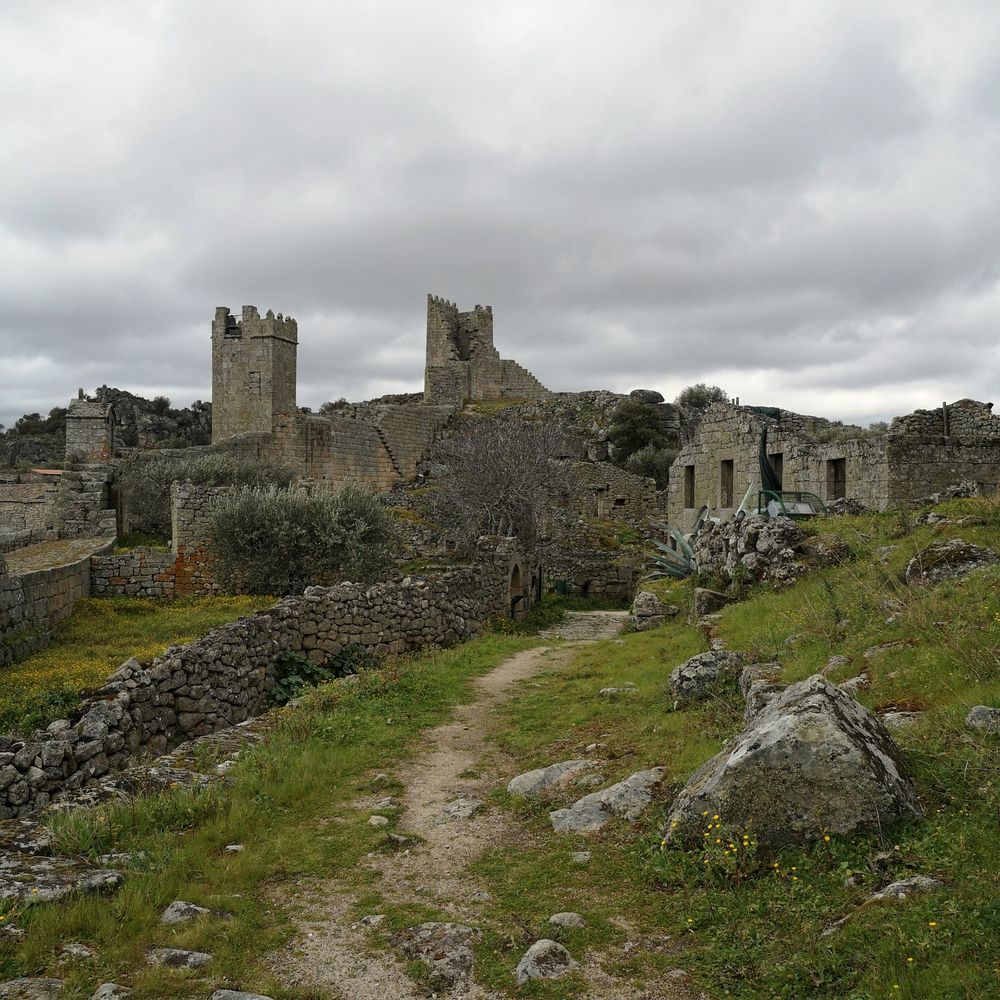 Aldea en ruinas con dos torres medievales bajo un cielo nublado