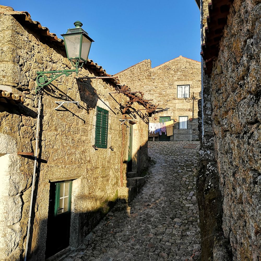 Calle empinada de granito con farola verde y ropa tendida